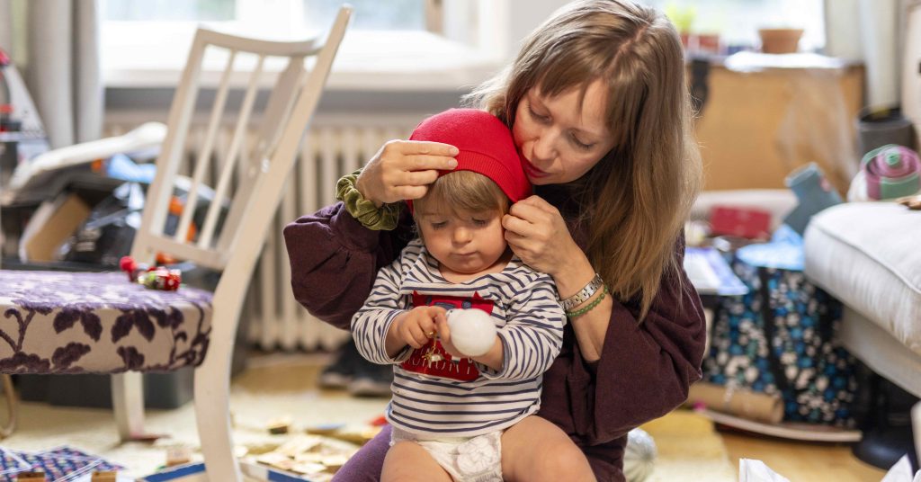 Lapsi istuu naisen sylissä lattialla