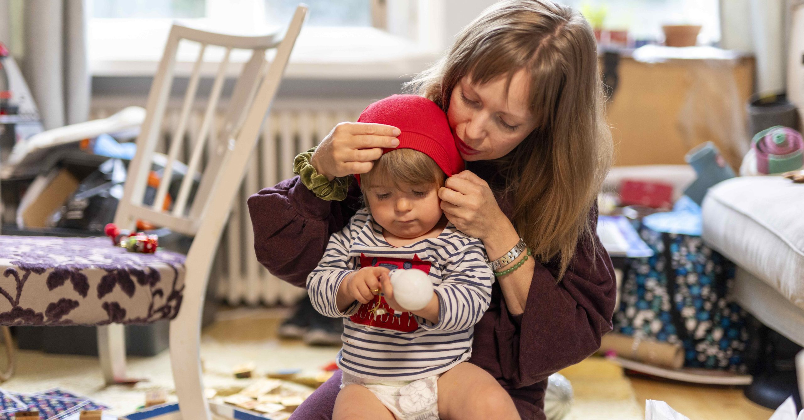 Lapsi istuu naisen sylissä lattialla